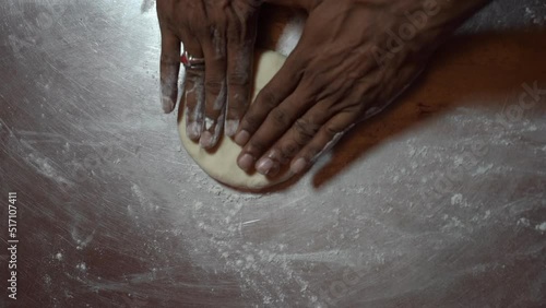 one man makiing dough for pizzza photo