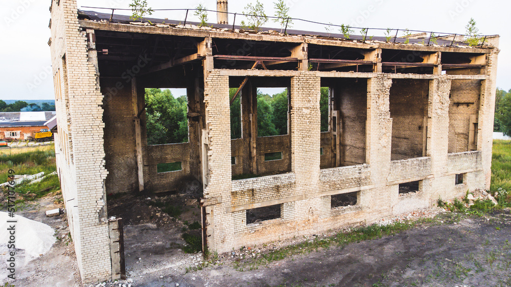 an abandoned brick building with a flat roof. Small windows without glass,