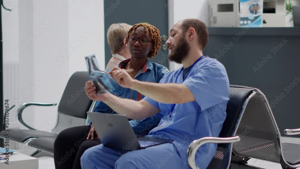 Female patient looking at radiography results with medical assistant, doing diagnosis examination in waiting room at reception area. Specialist showing bones x ray scan to woman at facility. Female patient looking at radiography results with medical assistant, doing diagnosis examination in waiting room at reception area. Specialist showing bones x ray scan to woman at facility.