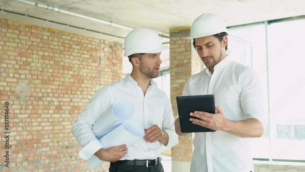 Two engineers discuss work with a tablet at the construction site Two engineers discuss work with a tablet at the construction site