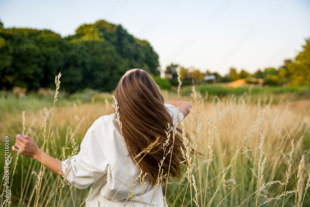 woman in wheat field on windy days with long hair woman in wheat field on windy days with long hair