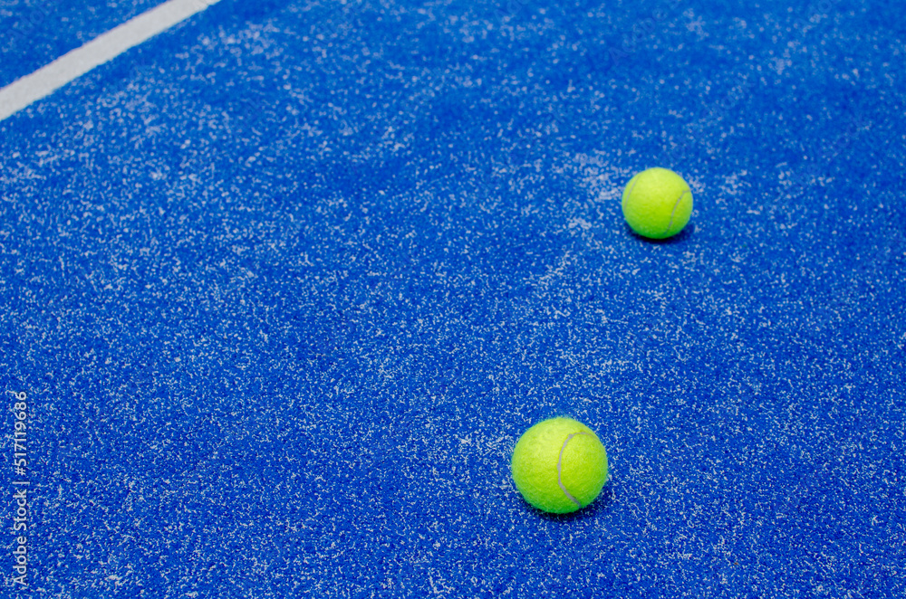 racket sports, five balls on the lines of a blue paddle tennis court