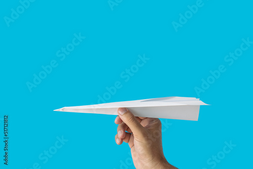 White paper airplane in the hand on a blue background with copy space.Travel concept photo