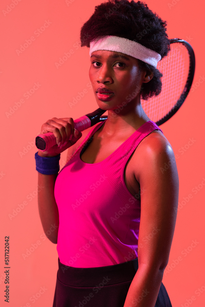 Vertical image of african american female tennis player in pink neon lighting Vertical image of african american female tennis player in pink neon lighting