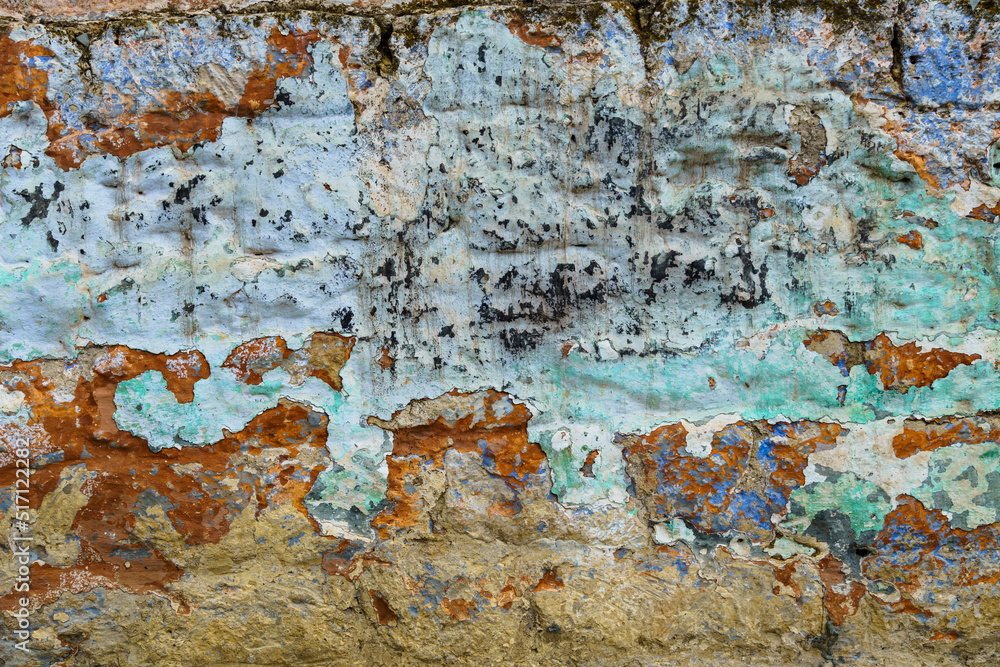 the surface of an old clay wall, weathered layers crumble, painted in different colors, for background or texture, an old house in the village