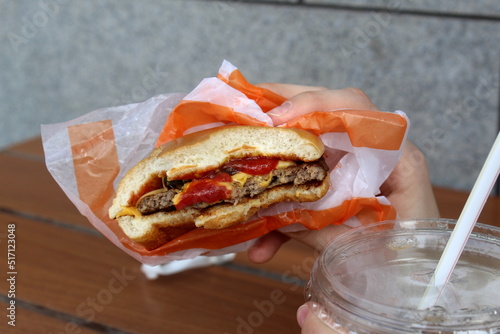 In a cafe at the table, a woman's hand holds a bitten sandwich. photo