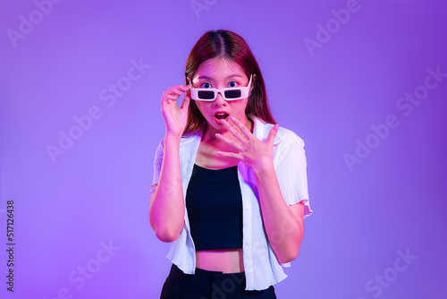 Young asian woman in black tank top and white shirt wearing sunglasses posing wow and surprised isolated purple color background.