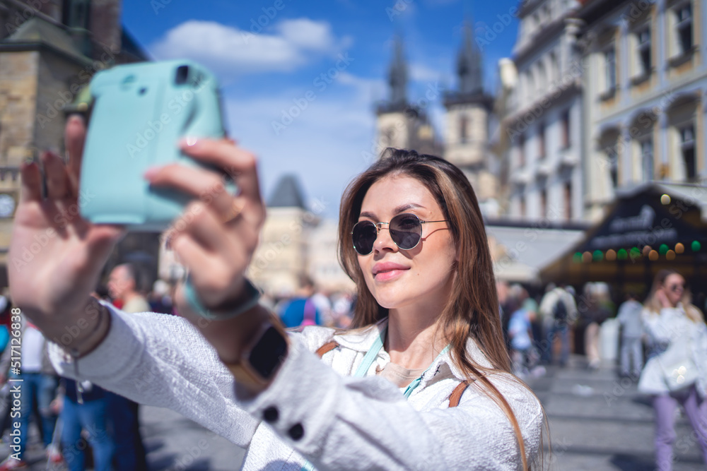 Woman taking selfie on instant camera on street