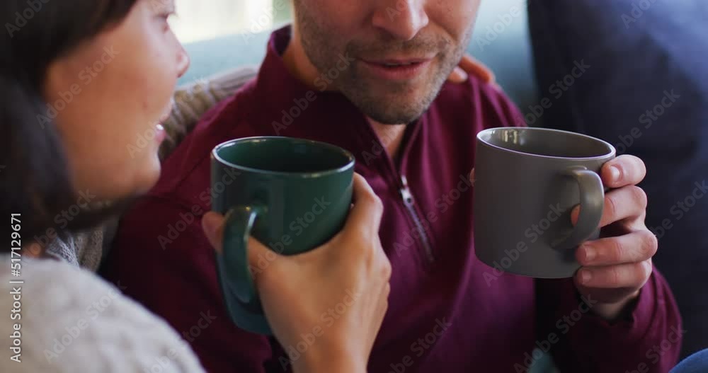 Video of back view of happy diverse couple sitting on sofa and drinking coffee Video of back view of happy diverse couple sitting on sofa and drinking coffee