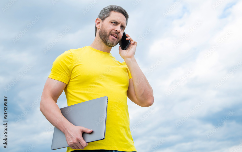 man with laptop speaking on smartphone on sky background. modern life man with laptop speaking on smartphone on sky background. modern life