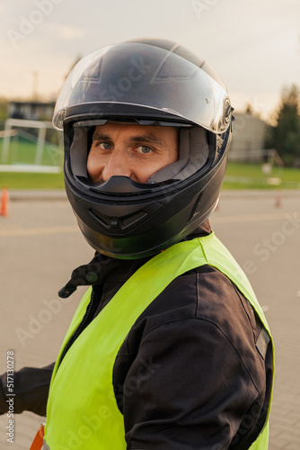 Motorcyclist in a driving lesson. Lessons in auto and motorcycle school. A student in a special uniform drives a motorcycle. Summer training on a moped. Student and teacher.  © Аня Марченко