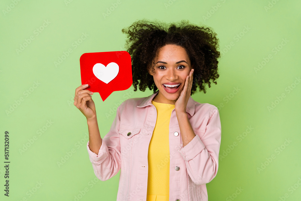 Photo of astonished millennial girl hand cheek hold paper like card isolated on green color background Photo of astonished millennial girl hand cheek hold paper like card isolated on green color background