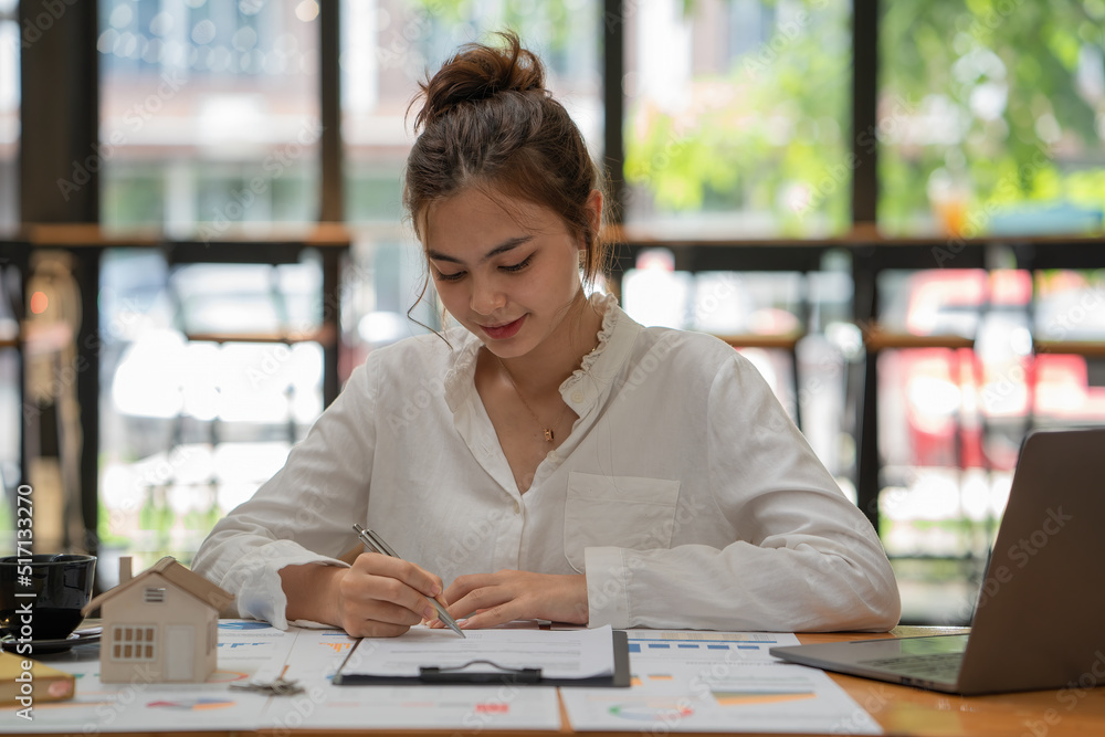 Young beautiful woman using her laptop while sitting in a chair at her working place. Young beautiful woman using her laptop while sitting in a chair at her working place.