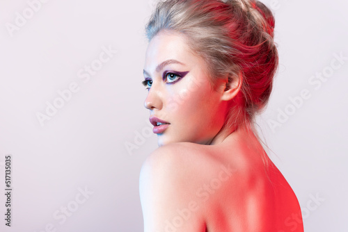 Pretty blonde young woman with naked shoulders and fashionable make up with colorful arrows on eyes
