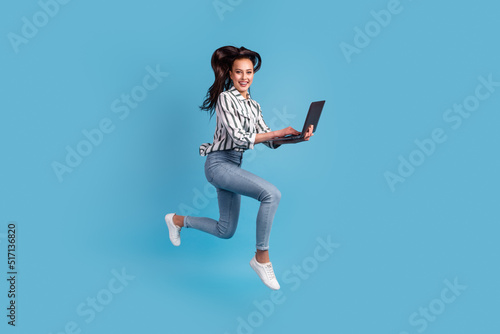 Photo of pretty charming woman dressed shirt holding using device jumping running isolated blue color background