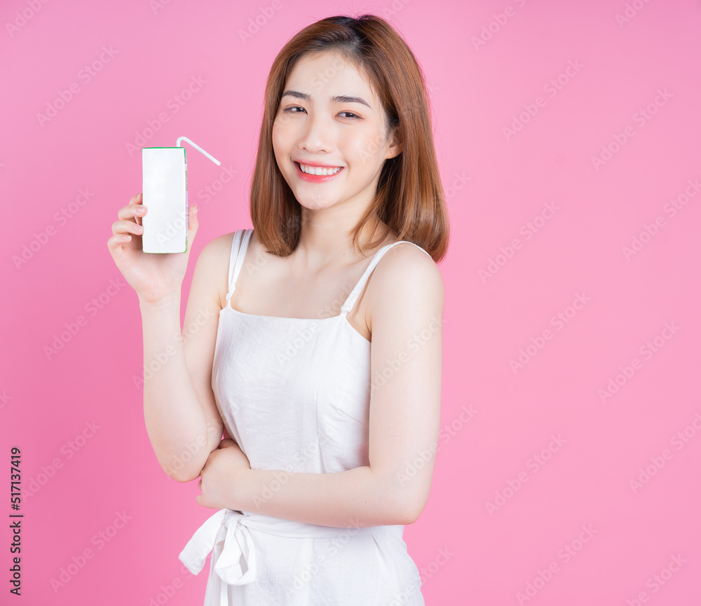 Image of young Asian woman holding milk carton on pink background Image of young Asian woman holding milk carton on pink background