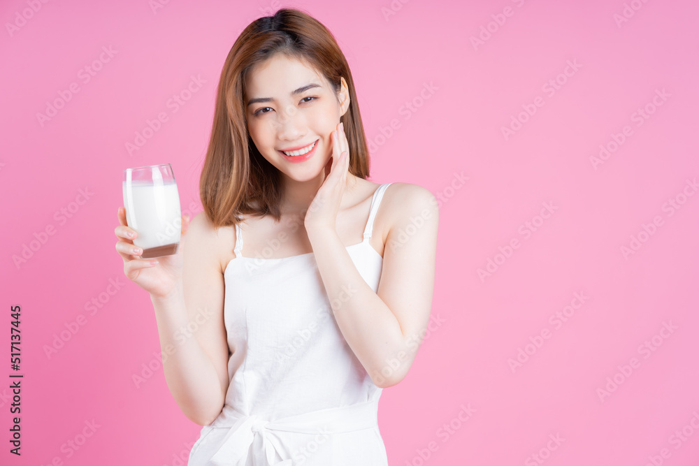 Image of young Asian woman drinking milk on pink background Image of young Asian woman drinking milk on pink background