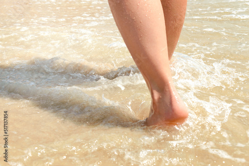 Woman feet walking on beach barefoot  closeup of foot coming out of water.