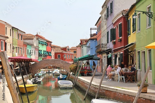 Burano water canal, Burano island, bridge over the canal, colorful houses on the shore of the canal, restaurant on the shore, houses in bright colors