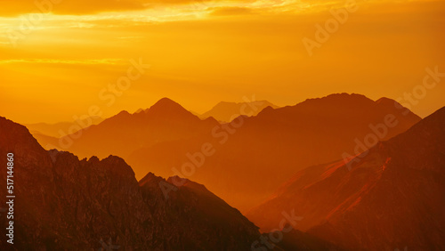 Silhouetted orange mountains and horizon at Fagaras mountains, Moldoveanu peak. mountains at sunset, national park. Scenic View Of Mountains Against Cloudy Sky During Sunset photo