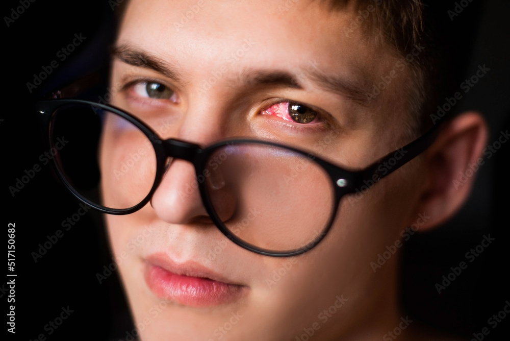 portrait of a guy with red eyes and glasses. Pain and despair. Black background portrait of a guy with red eyes and glasses. Pain and despair. Black background