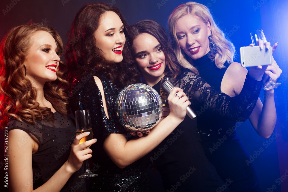 Group of partying women clinking flutes with sparkling wine and make selfie.
