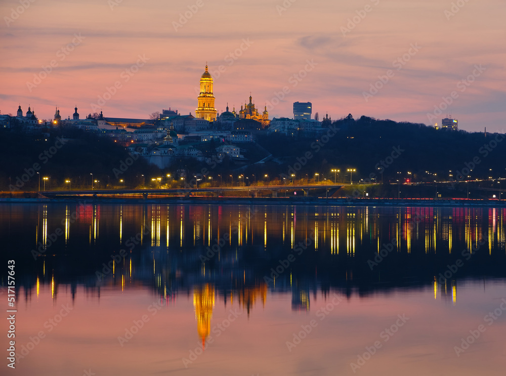 Kiev-Pechersk Lavra and city lights. Silhouette panorama at sunset of the colorful sky over the Dnieper river with passing ducks in Kyiv