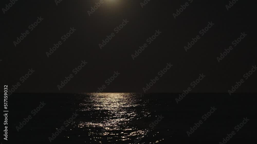A large full moon illuminates the ocean. Waves, light on the water. A large full moon illuminates the ocean. Waves, light on the water.