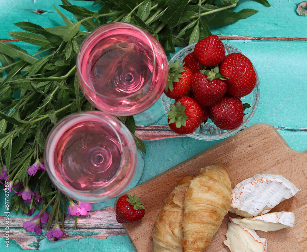 Sunny day in a garden. Fresh fruit, flowers, cheese and wine on a table. Green grass on a background. Blank space for text. 
