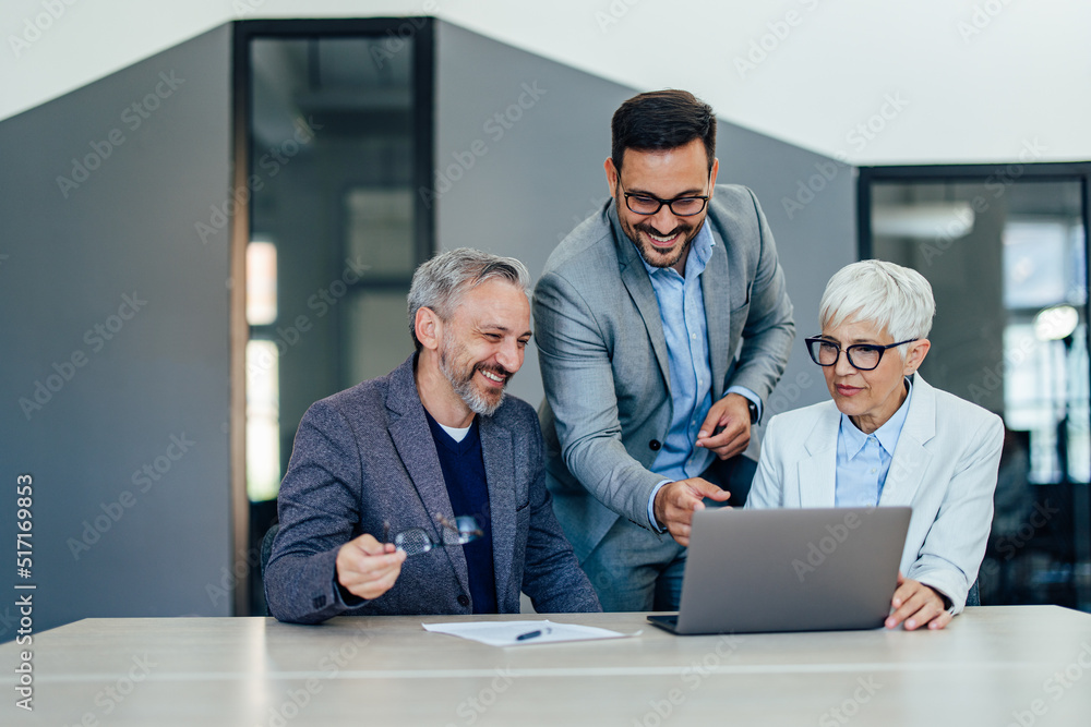 People working as a team, using a laptop, reading something online. People working as a team, using a laptop, reading something online.