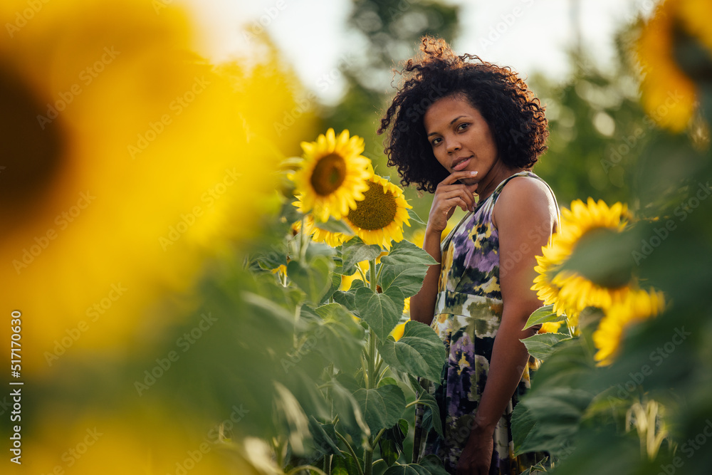 Portrait of a serious-looking woman, posing for the camera, standing in the field of sunflowers. Portrait of a serious-looking woman, posing for the camera, standing in the field of sunflowers.