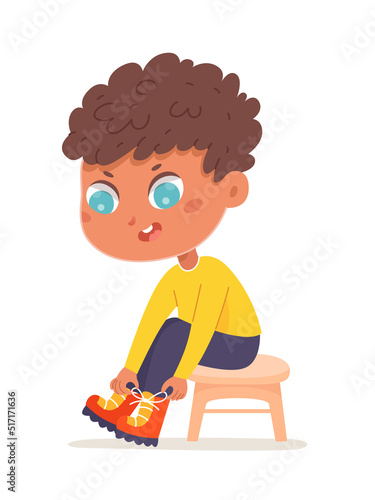 Cute boy putting on boots, isolated adorable little kid sitting on chair to put on shoes