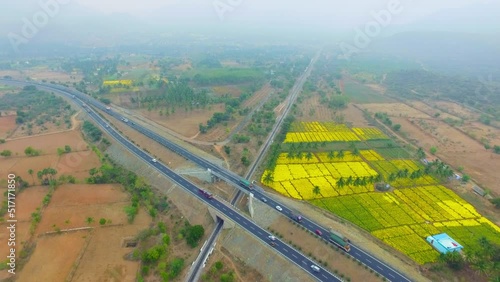 A railway track pass beneath a bridge and vehicles on a state highway surrounded by farmland photo