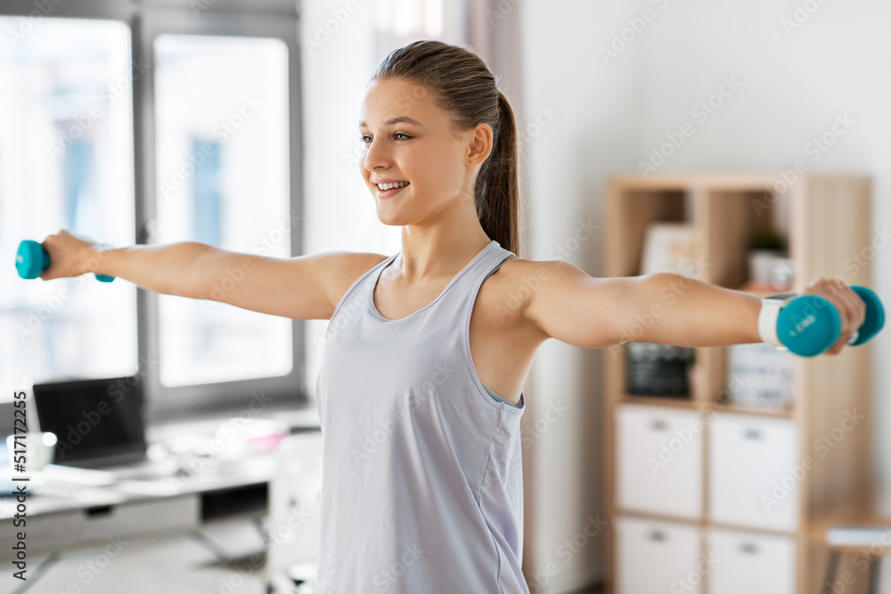fitness, sport and healthy lifestyle concept - happy teenage girl with dumbbells exercising at home