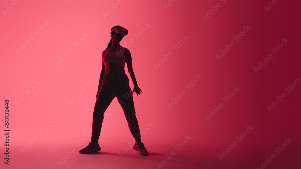 Sporty young woman wearing virtual reality goggles in neon light