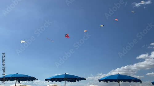 Kites flying above beach umbrellas