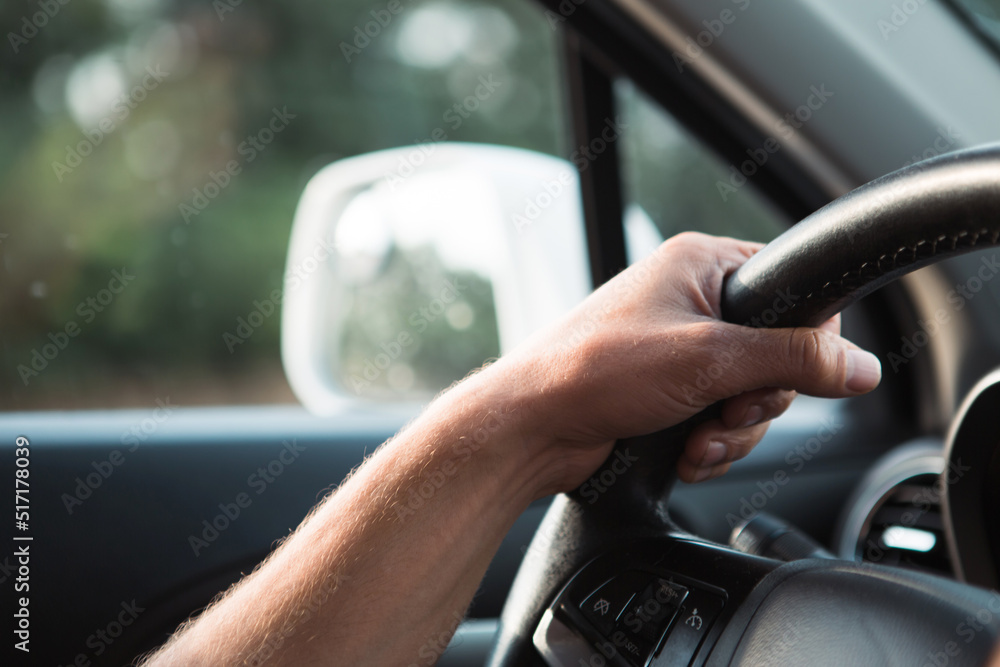 The driver's hand on the steering wheel of the car. Driving, traffic rules, safety at the wheel.