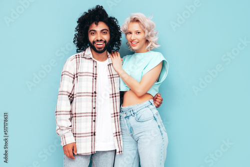 Smiling beautiful woman and her handsome boyfriend. Sexy cheerful multiracial family having tender moments on beige background in studio. Multiethnic models hugging. Embracing each other.Love concept