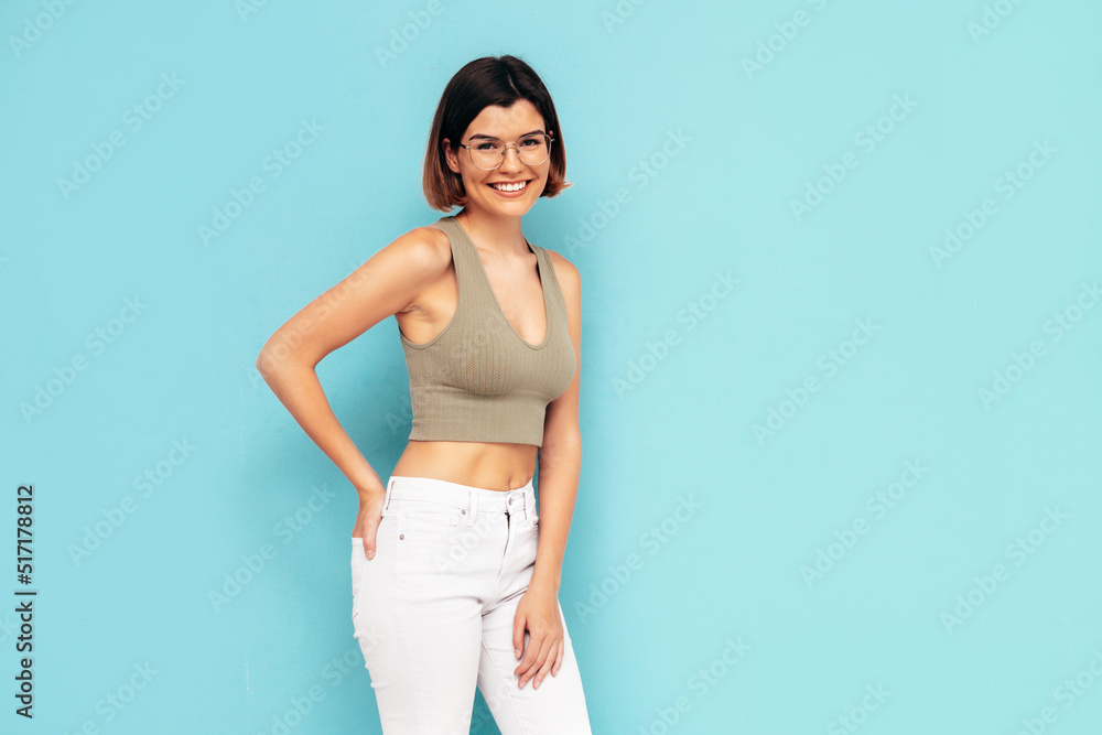 Smart young beautiful smiling female in trendy summer clothes. Carefree woman posing near blue wall in studio. Sexy positive model having fun indoors. Cheerful and happy. In glasses, spectacles Smart young beautiful smiling female in trendy summer clothes. Carefree woman posing near blue wall in studio. Sexy positive model having fun indoors. Cheerful and happy. In glasses, spectacles
