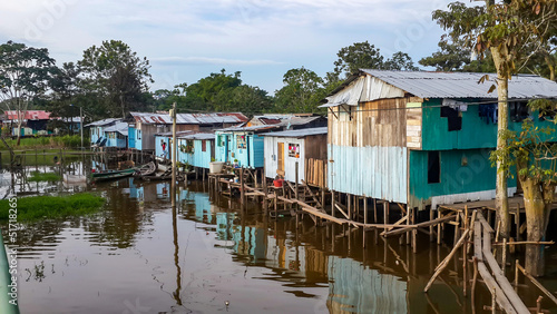 Puerto Narino, Colombia - Feb. 13, 2017: Beautiful stilt houses built on piles over the brown water of Amazon river. Favela slums of local Indian tribes. Poor housing protecting against flooding.  photo