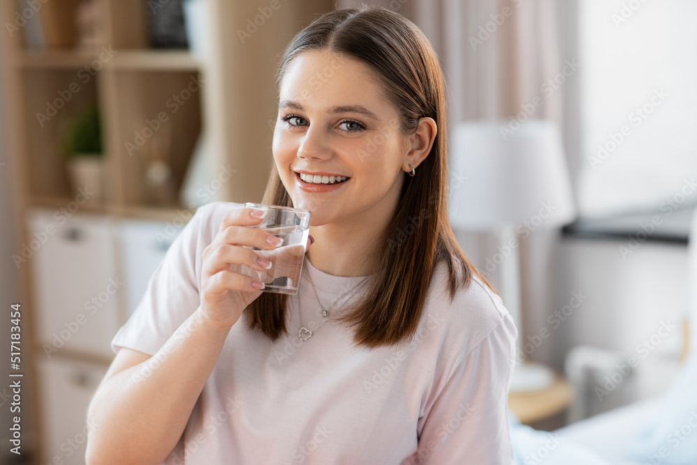 health and people concept - happy smiling girl with glass drinking water at home health and people concept - happy smiling girl with glass drinking water at home