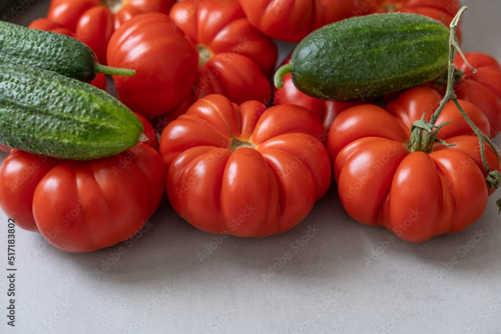Fresh ripe ribbed red tomatoes and cucumbers, with sepal, harvest. Seasonal vegetables. Copy Space. Fresh ripe ribbed red tomatoes and cucumbers, with sepal, harvest. Seasonal vegetables. Copy Space.