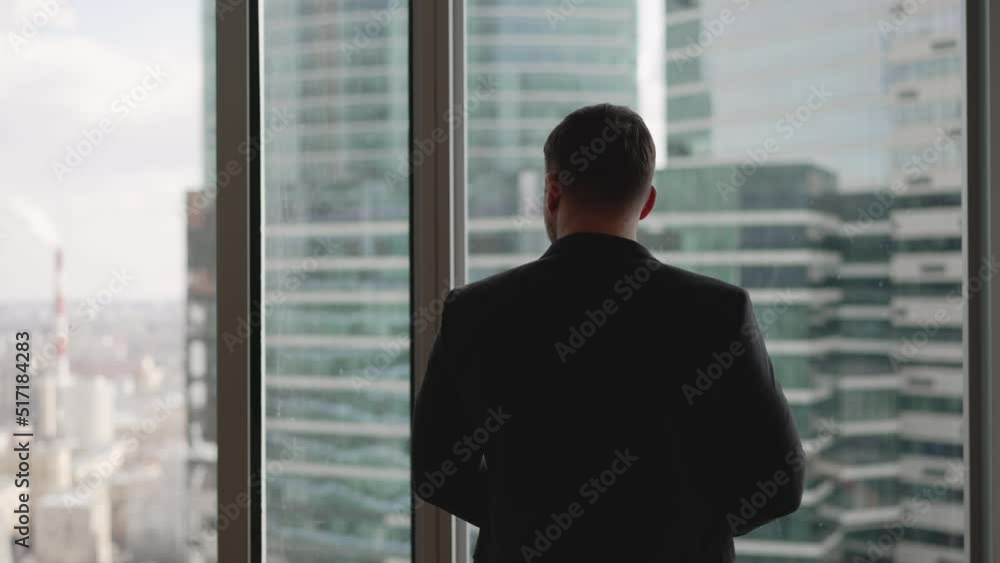 A businessman in a suit stands at the window against the backdrop of skyscrapers. A successful business man in a suit stands against the backdrop of the panoramic windows of a skyscraper. Successful A businessman in a suit stands at the window against the backdrop of skyscrapers. A successful business man in a suit stands against the backdrop of the panoramic windows of a skyscraper. Successful