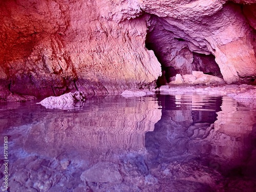 Amazing cave grotto with surreal rocks. Scenic reflection of rock formations in calm sea water.