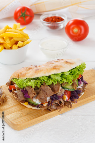 Döner Kebab Doner Kebap fast food meal in flatbread with fries on a kitchen board portrait format