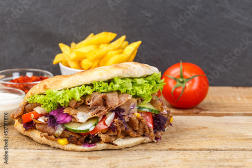 Döner Kebab Doner Kebap fast food meal in flatbread with fries on a wooden board and copyspace copy space © Markus Mainka