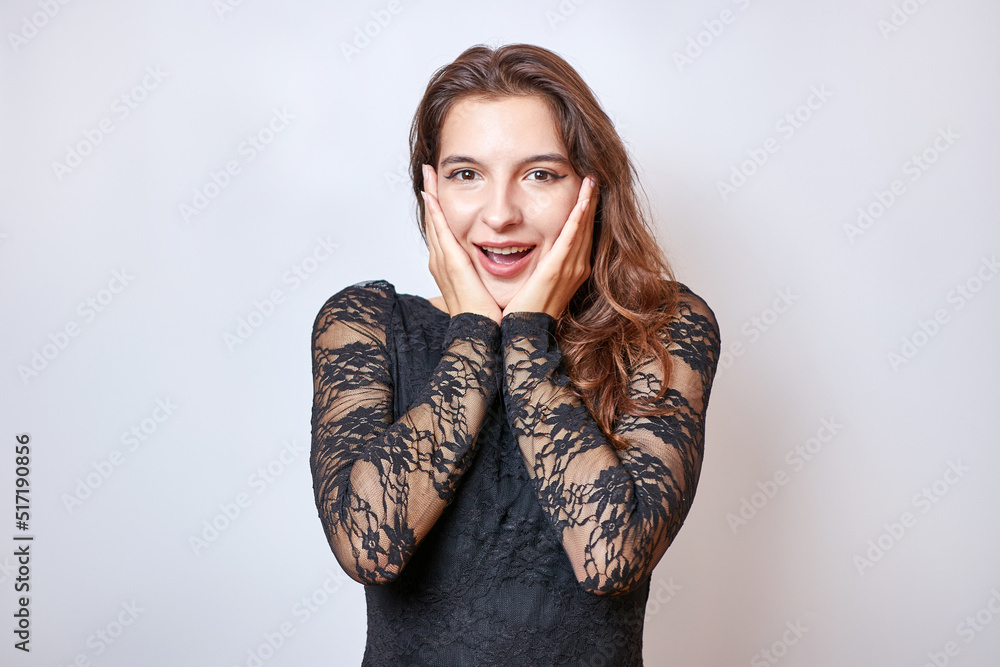 A beautiful girl in a black dress is delighted with what she saw. Concept of gestures and emotions. A beautiful girl in a black dress is delighted with what she saw. Concept of gestures and emotions.