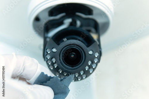 A technician cleans the lens of a CCTV camera from dust. Small depth of field.