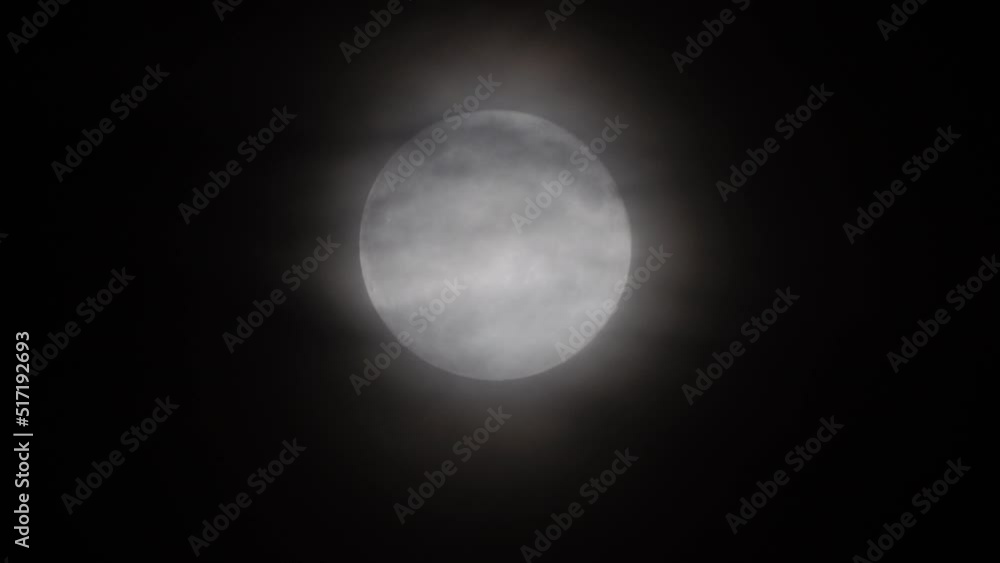 Glowing huge full moon as seen from earth through the clouds against starry night sky. Large full moon moves across the sky, moon makes its way from bottom left frame to top right. Glowing huge full moon as seen from earth through the clouds against starry night sky. Large full moon moves across the sky, moon makes its way from bottom left frame to top right.