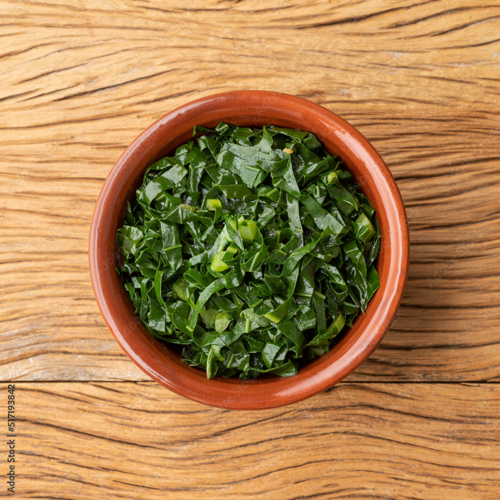 Cooked kale strips, typical brazilian feijoada sidedish in a bowl over wooden table